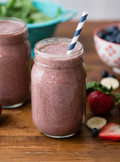 Two berry smoothies surrounded by fresh berries