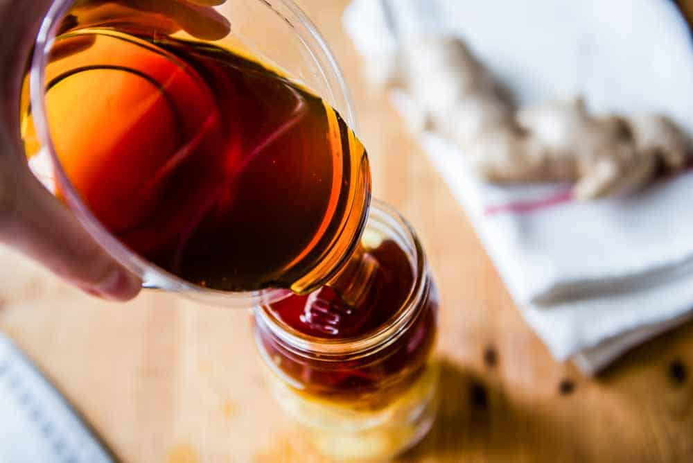 Pouring raw honey into Ginger Lemon Honey Tea jar.