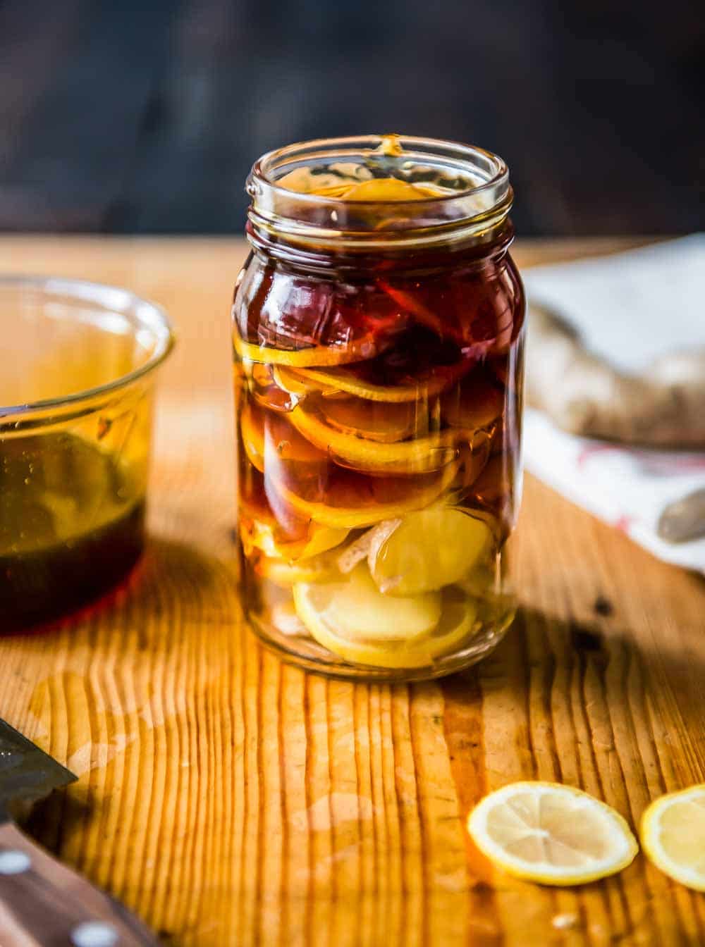 Home remedy for sore throat in a glass jar with honey, lemon and ginger.