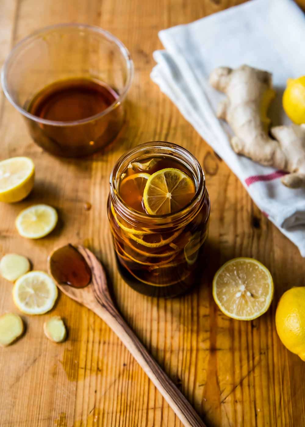 homemade tea concentrate to help with sore throats in a glass jar on a wooden counter top.