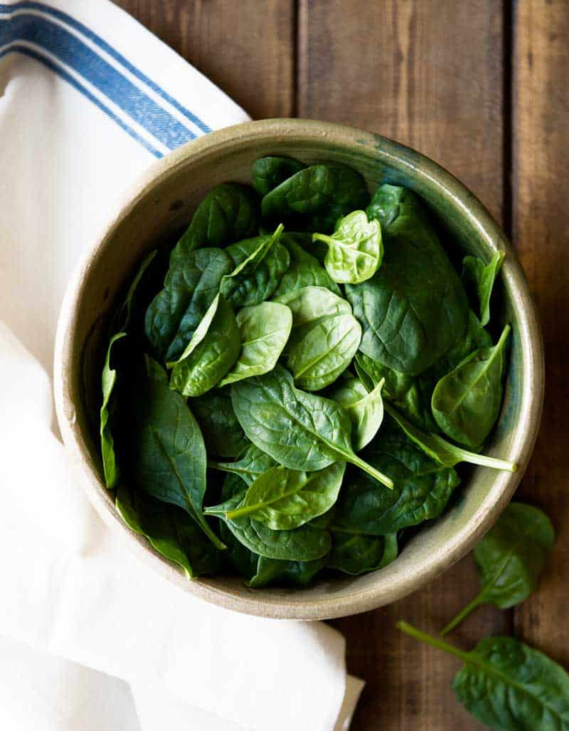ceramic bowl filled with raw baby spinach leafy greens