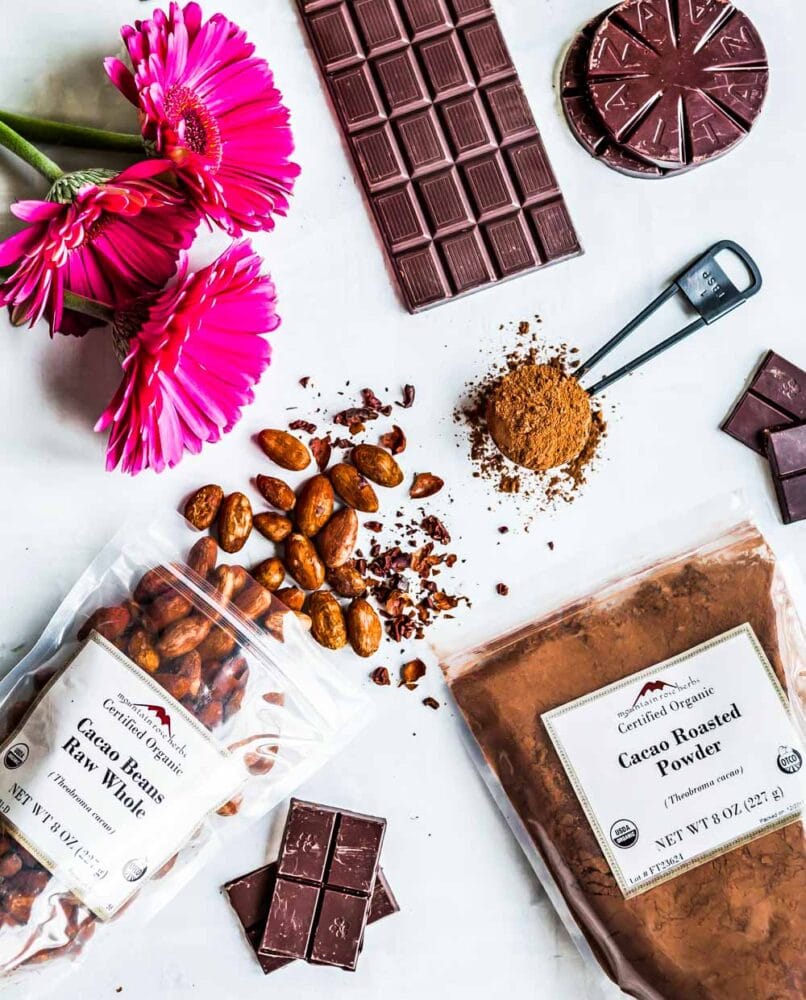 packages of raw cacao beans, cacao roasted powder and chocolate bars on a white counter top.