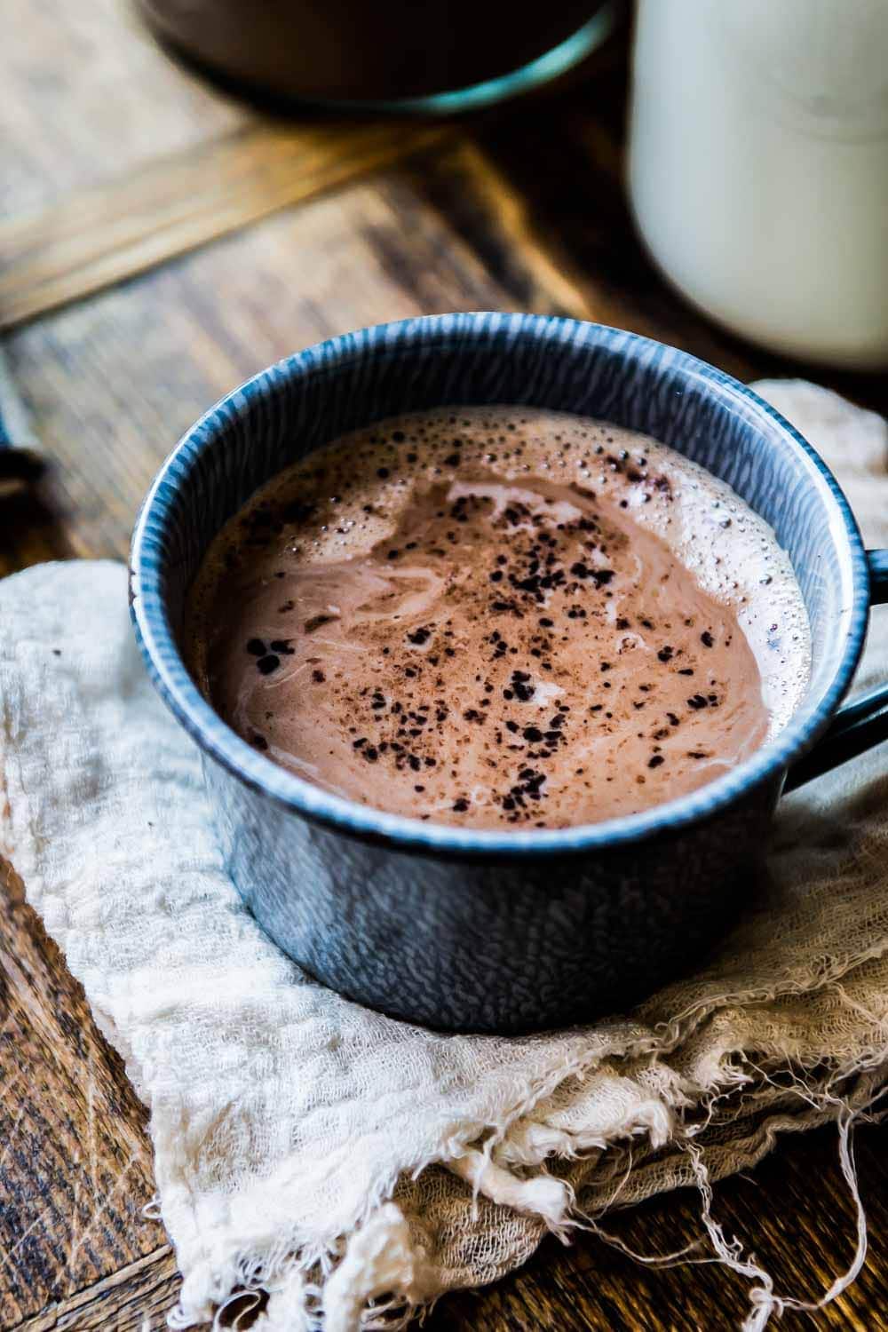 A blue mug filled with rich homemade hot chocolate placed on a woodgrain countertop.