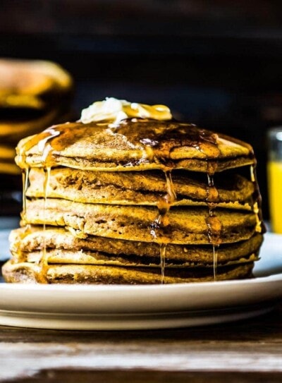 fresh stack of vegan pumpkin pancakes covered in syrup.