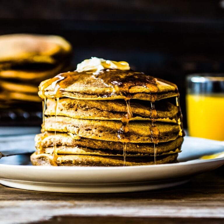 fresh stack of vegan pumpkin pancakes covered in syrup.