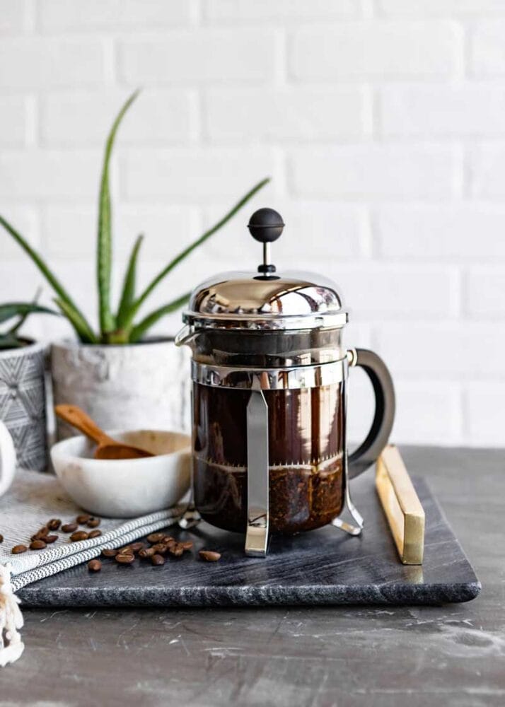 miniature sized french. press full of healthy coffee on marble slab tray