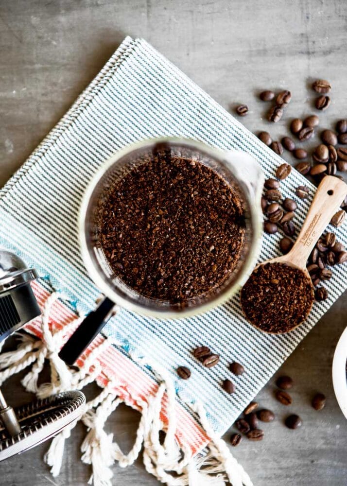 ground coffee close up on a spoon, with ground and whole bean coffee ready for a coffee recipe