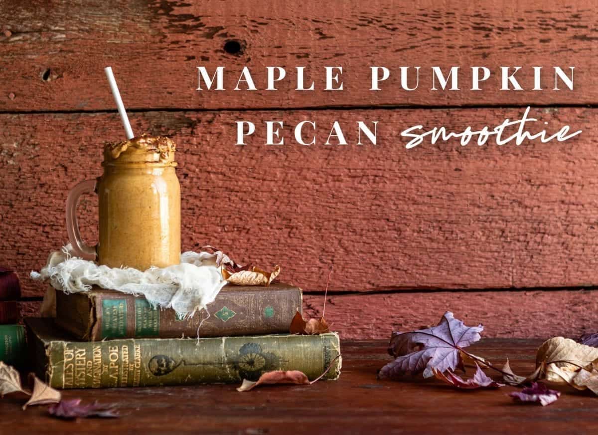 styled photo of pumpkin smoothie sitting on top of old books with red wood background and Maple Pumpkin Pecan Smoothie written across