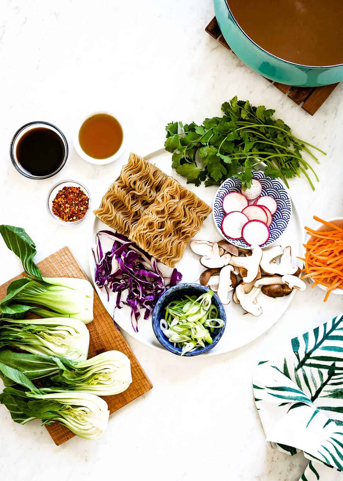 Ingredients for easy ramen including cilantro, radishes, ramen, carrots, mushroom, tamari, red pepper flakes, purple cabbage, bok choy and green onions.