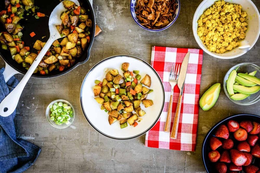 breakfast bowl on a white plate surrounded by other plant-based breakfast ingredients.