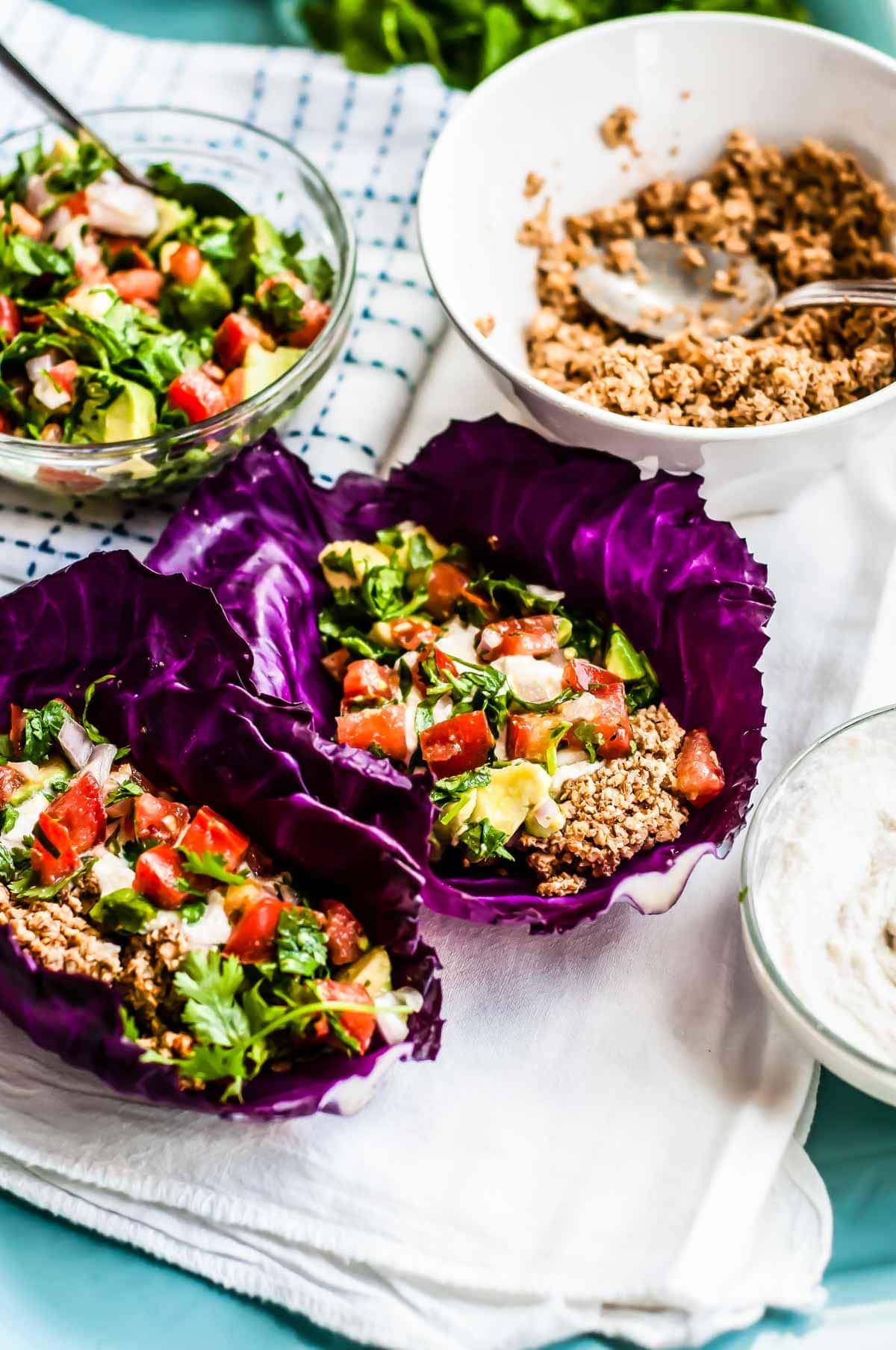 2 vegan tacos made with walnut taco meat on purple cabbage leaves.