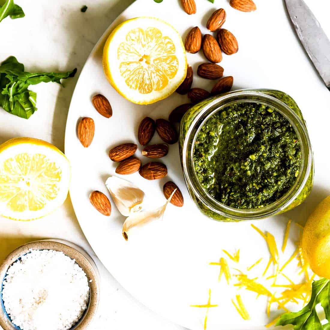 Small jar of lemon arugula pesto on a plate.