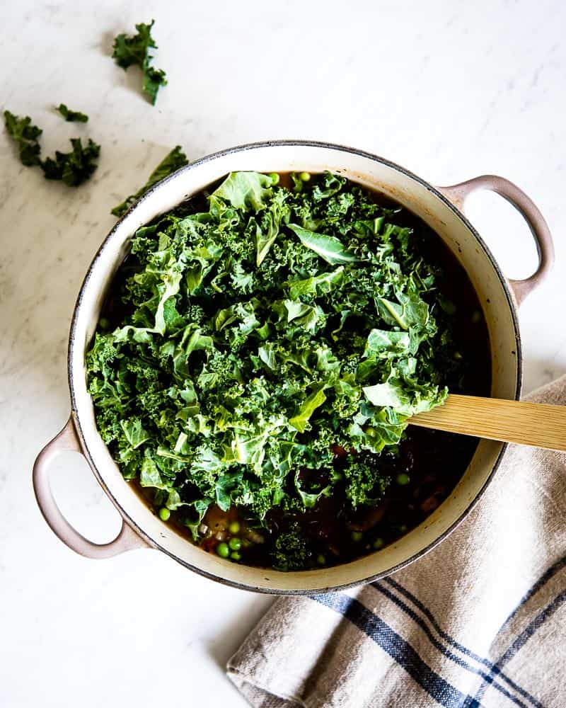 Fresh kale leaves chopped into a pot of soup.