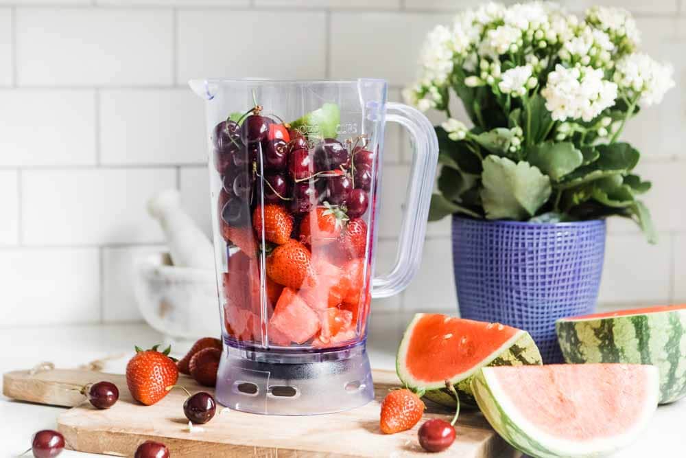 Blender filled with watermelon, cherries, strawberries and lime for smoothie