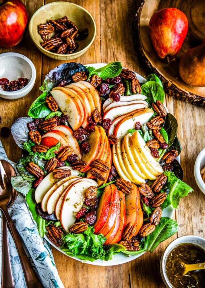 a beautifully plated fall salad with sliced pears and candied pecans