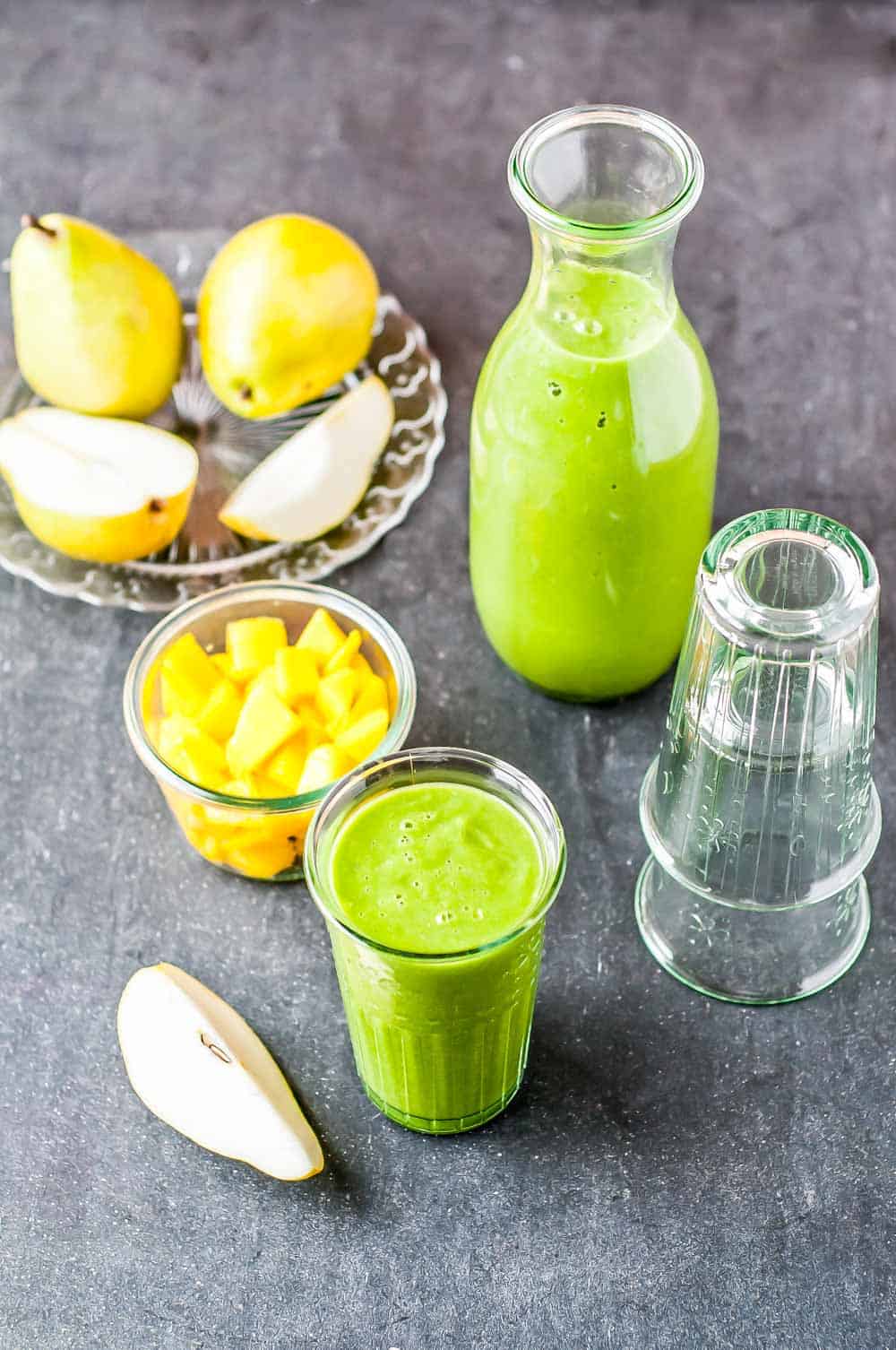 a tall glass of brain food smoothie along side sliced pears and pineapple.