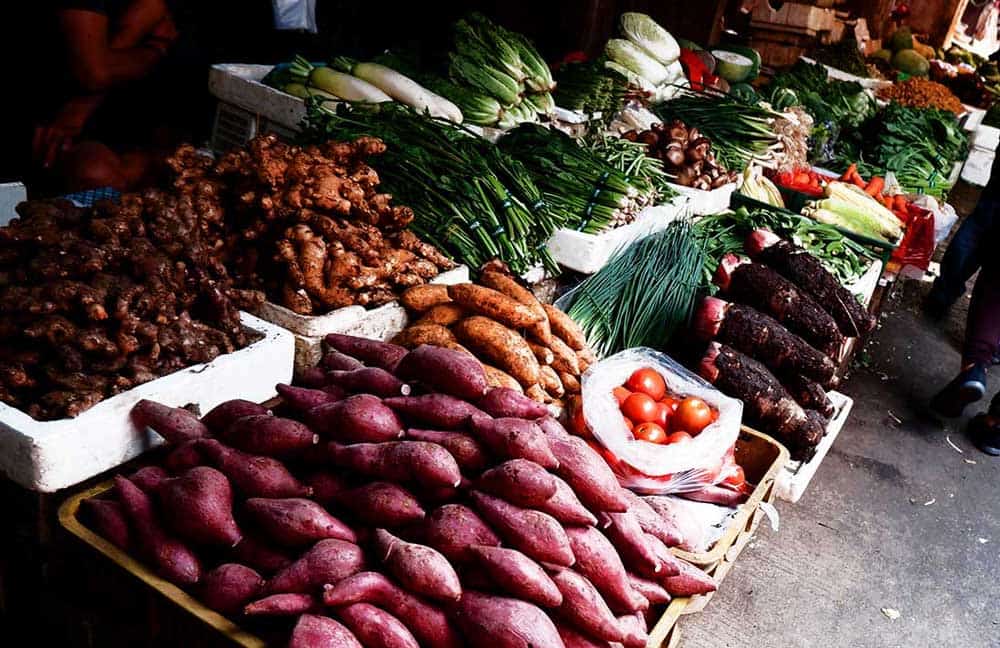 open stand with fresh, whole food produce including a bin full of sweet potatoes ready to be turned into oven baked sweet potatoes