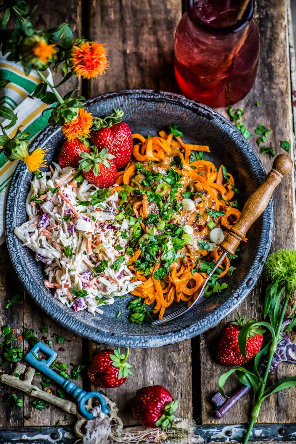 beautifully plated bowl with sweet potato noodles topped with almond butter sauce and slaw.