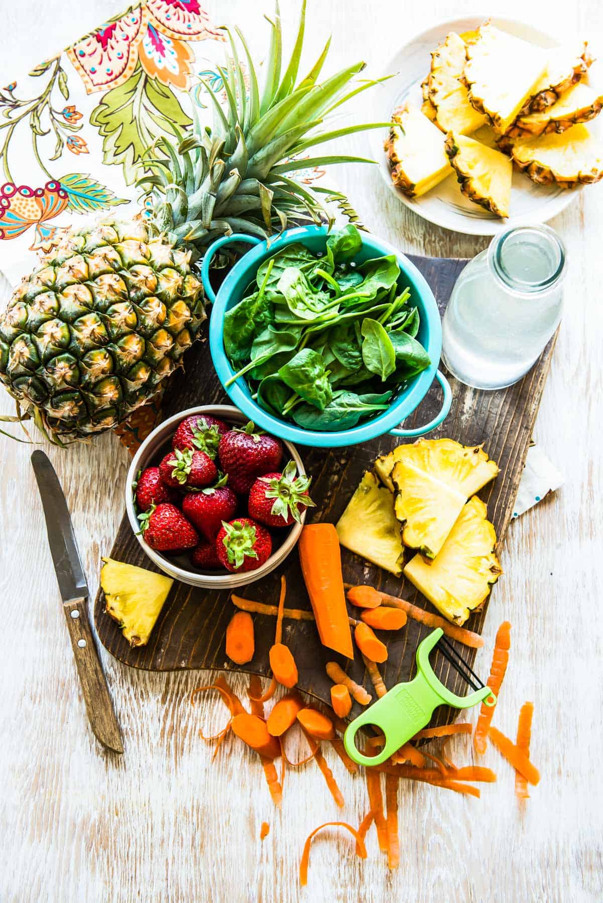 Ingredients in a carrot smoothie including pineapple, coconut water, spinach, strawberries and carrot.