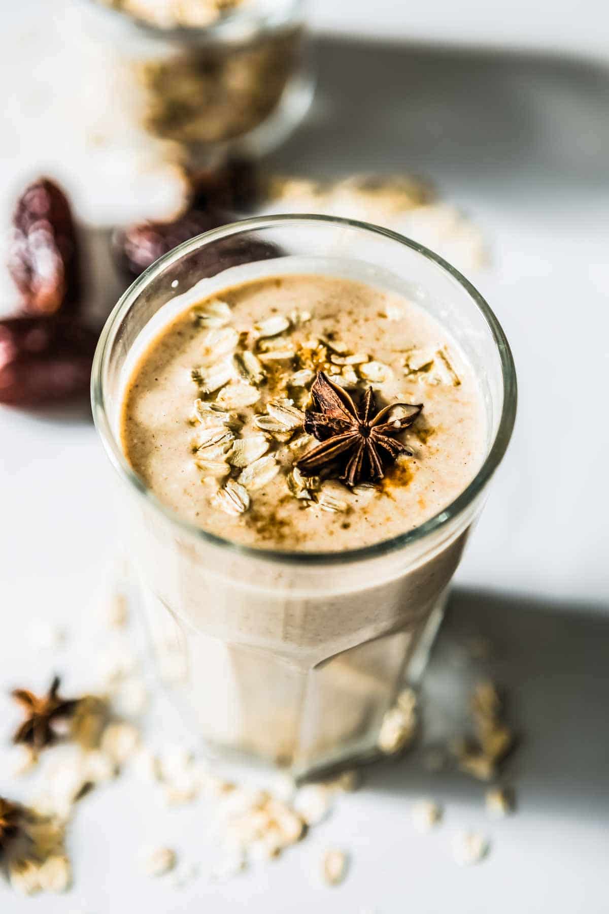Cinnamon date smoothie poured into a glass with anise on top and dash of cinnamon.