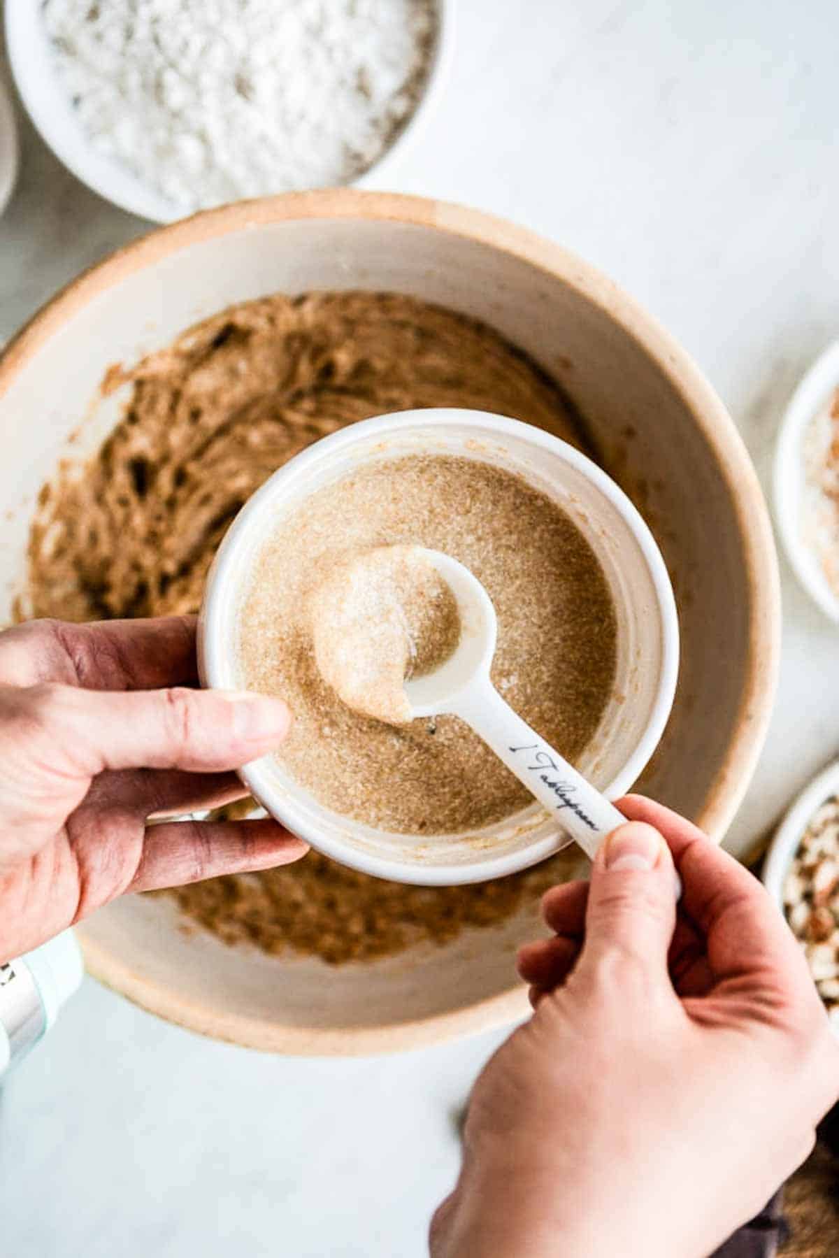 a bowl of flax egg over a bowl of mixed ingredients for a vegan chocolate chip cookie recipe.