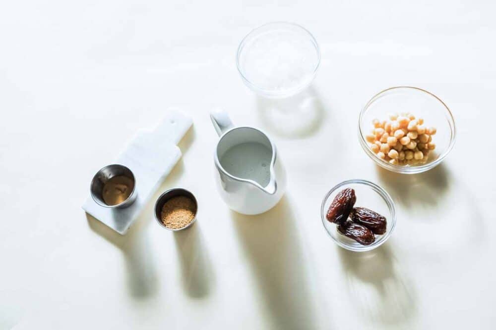 ingredients for a caramel protein shake including coconut oil, chickpeas, medjool dates, dairy-free milk, cashew butter and coconut sugar.