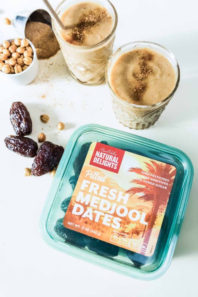 green container of Natural Delights pitted Fresh Medjool Dates on a white countertop.