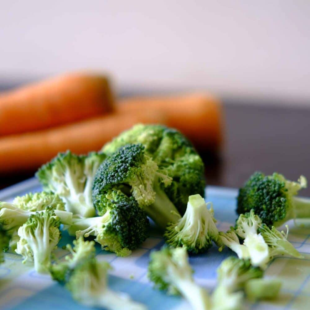 fresh broccoli florets chopped on a table. 