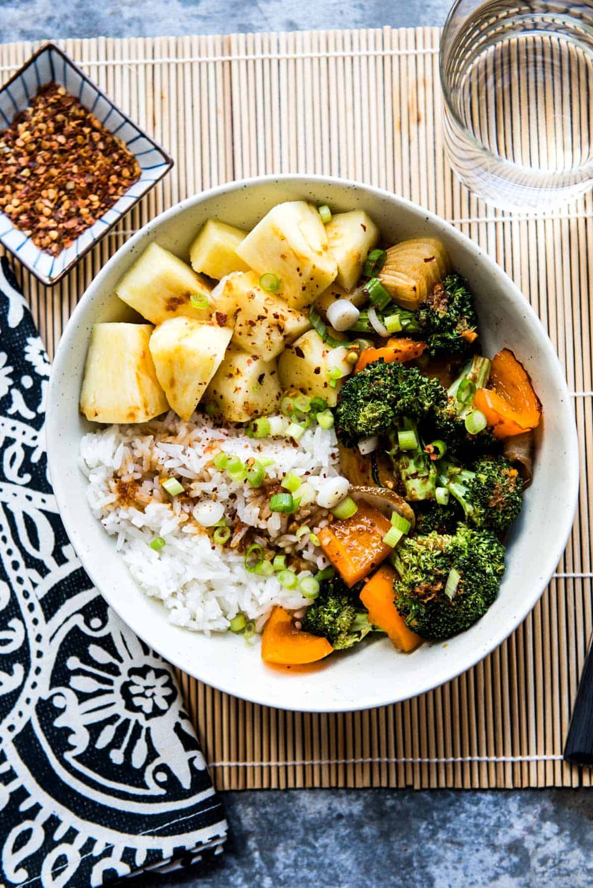 teriyaki rice bowl with pineapple, broccoli and carrots in a white bowl.