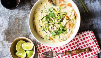 Creamy bowl of one of the 21-day cleanse detox recipes with red dotted table napkin, a fork, and fresh limes on the side.