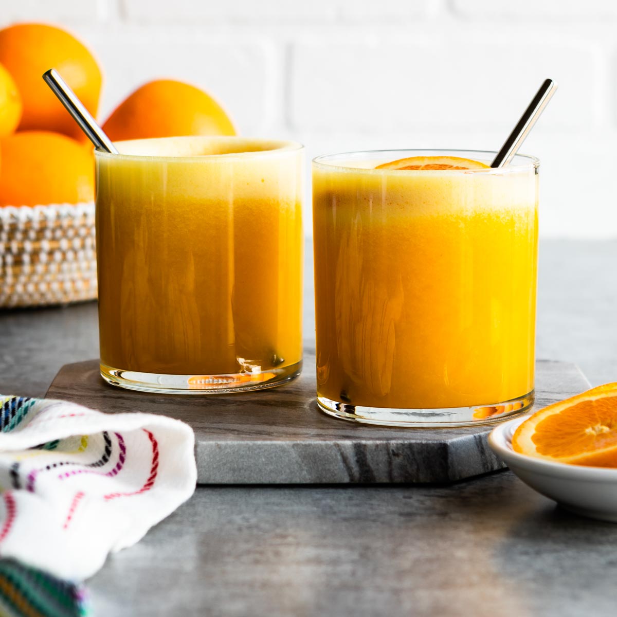 Bright orange smoothies in short glasses.