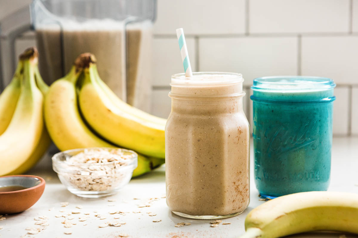 Creamy banana oatmeal smoothie beside whole bananas.