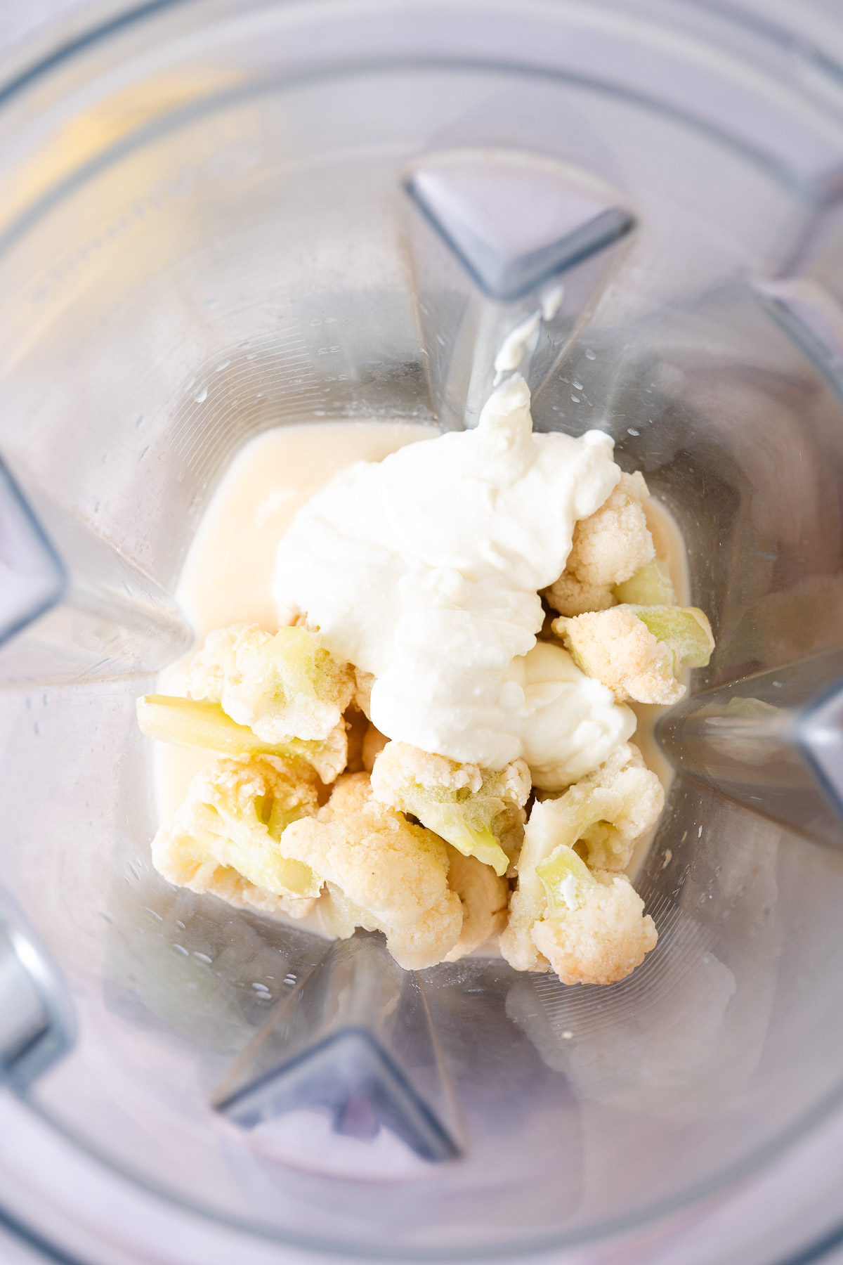 A blender containing banana slices, almond milk and Greek yogurt