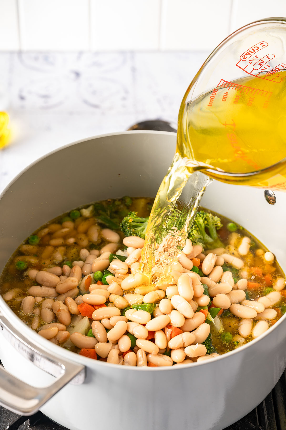 Pouring vegetable broth in a vegan soup recipe