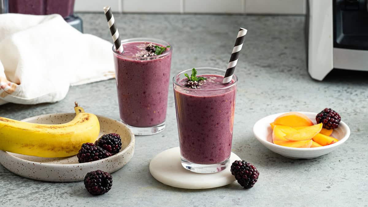 Two blackberry peach smoothies on the counter ready to enjoy
