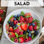 white bowl full of bright berry salad and a silver spoon.