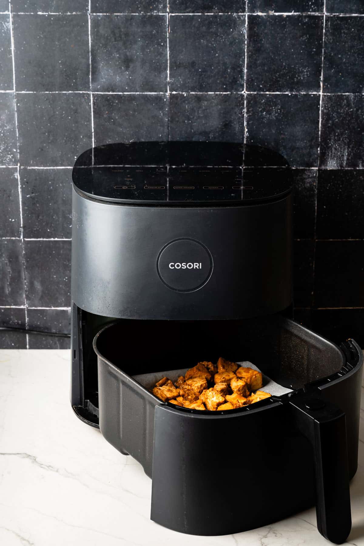 Coated tofu pieces placed in an air fryer basket