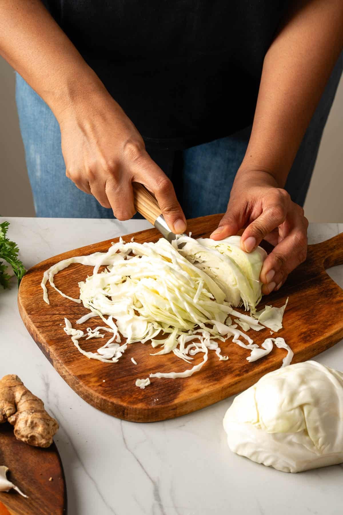 Thinly slicing green cabbage on a cutting board