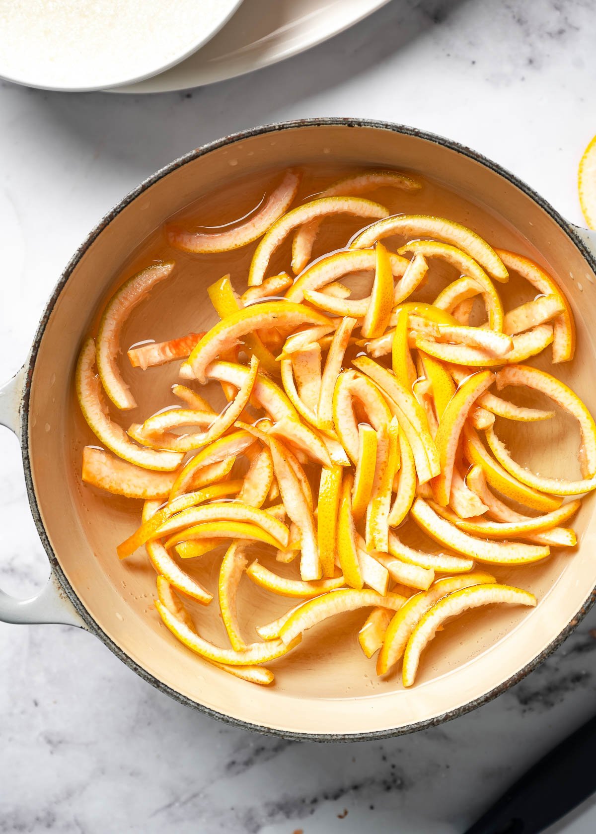 Grapefruit peel strips simmering in a pot of water