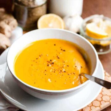 a vibrant bowl of carrot ginger soup with cracked pepper on top