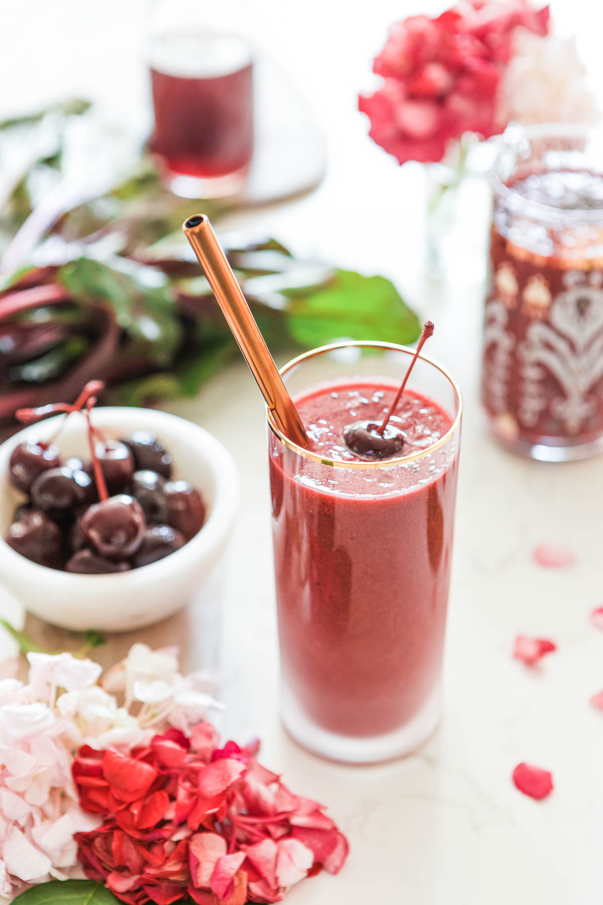 A refreshing cherry beet smoothie in a glass with a straw.