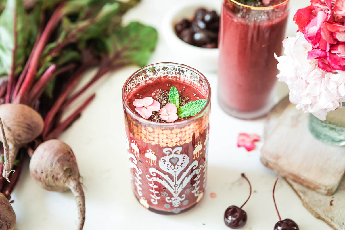 A glass of creamy beet smoothie on a countertop.