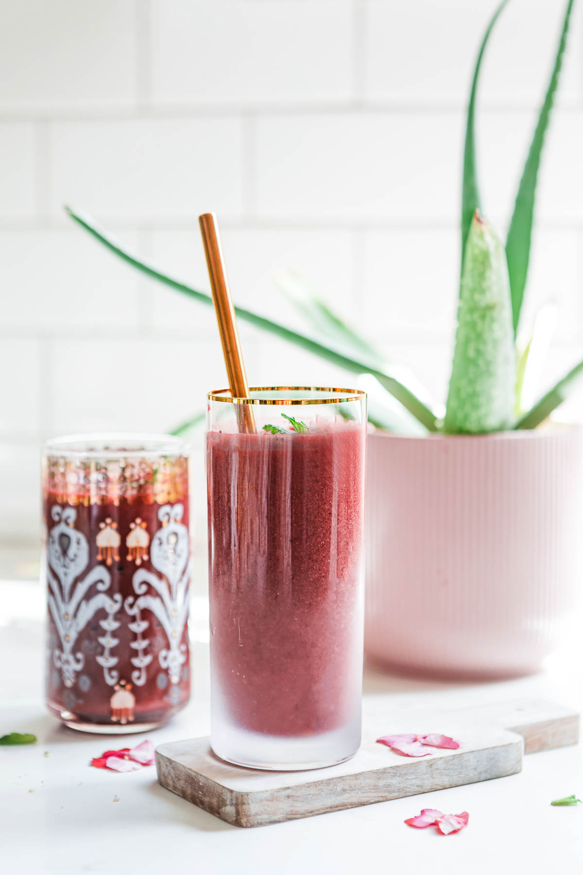 Refreshing cherry beet smoothie in a glass with aloe vera plant in background.