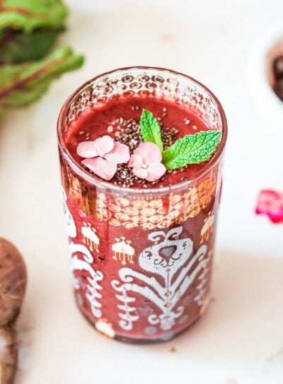 A glass of beet smoothie, garnished with fresh mint and ready to serve.