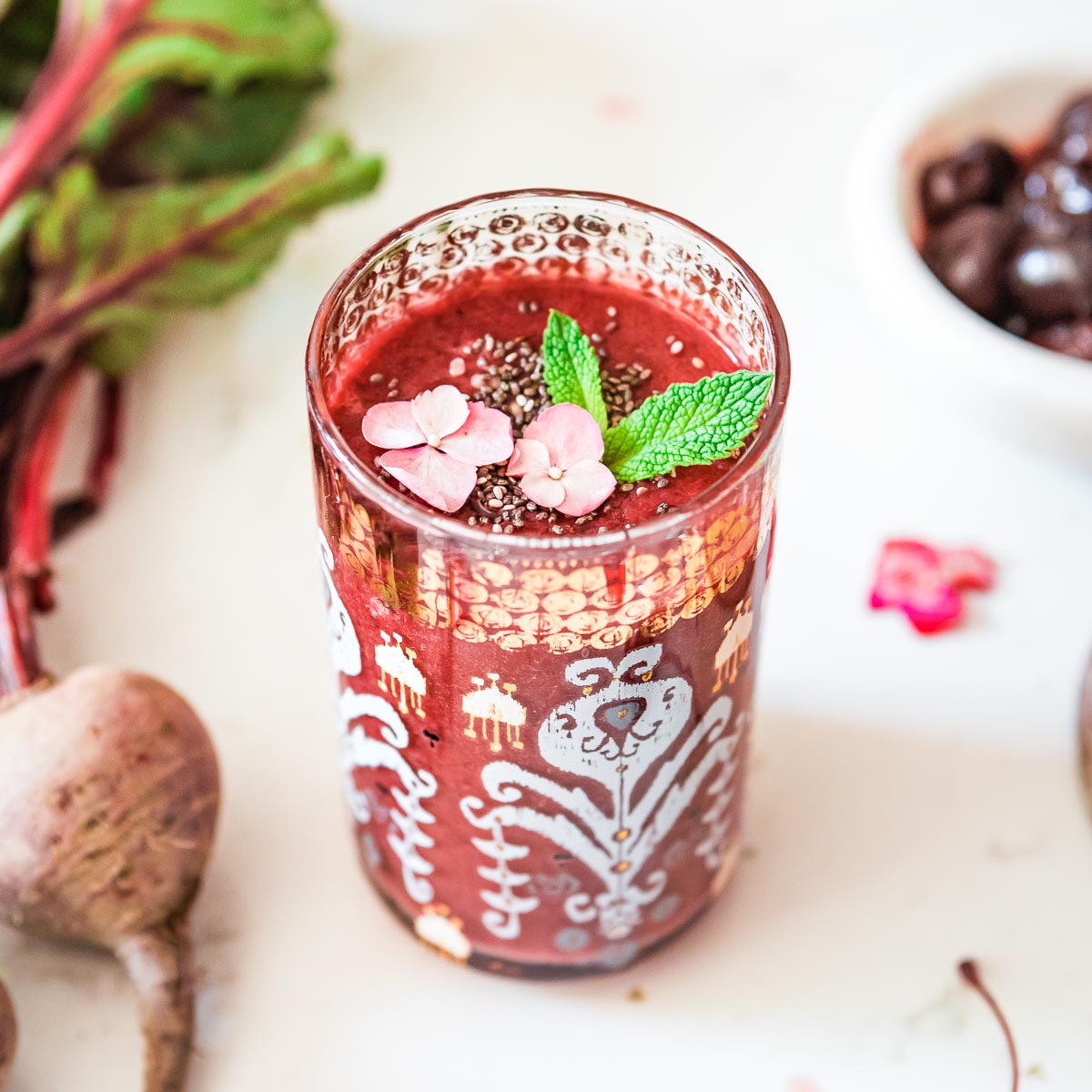A glass of beet smoothie, garnished with fresh mint and ready to serve.