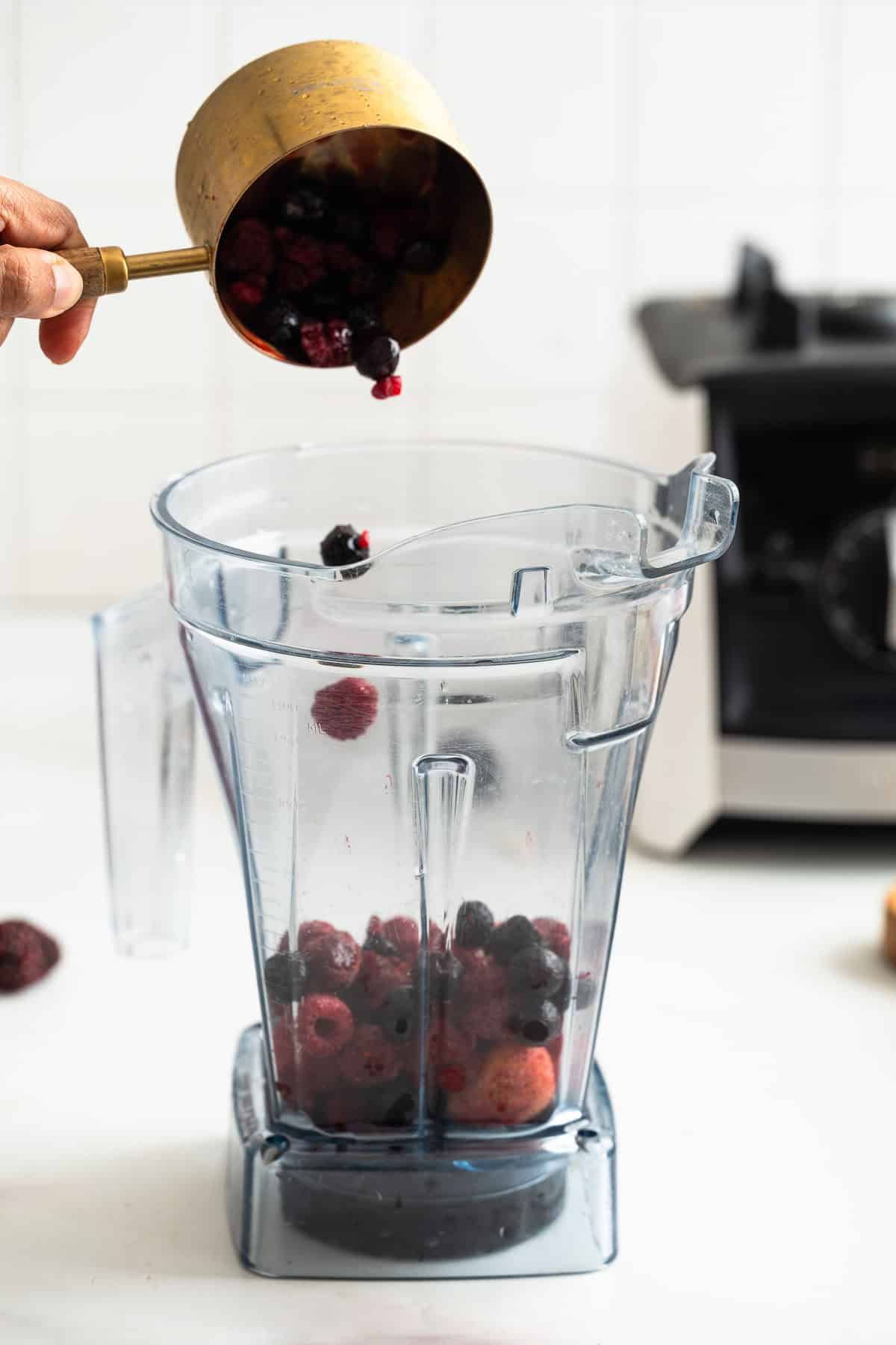 Adding fresh berries into a blender