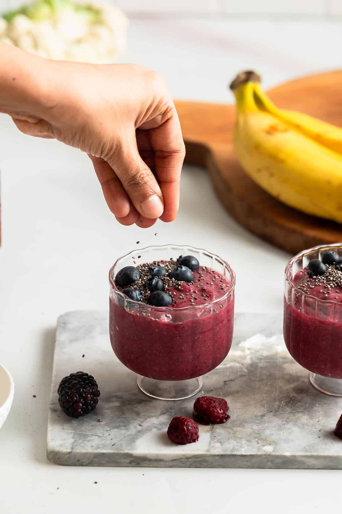 Sprinkling chia seeds over a glass of chia fruit smoothie