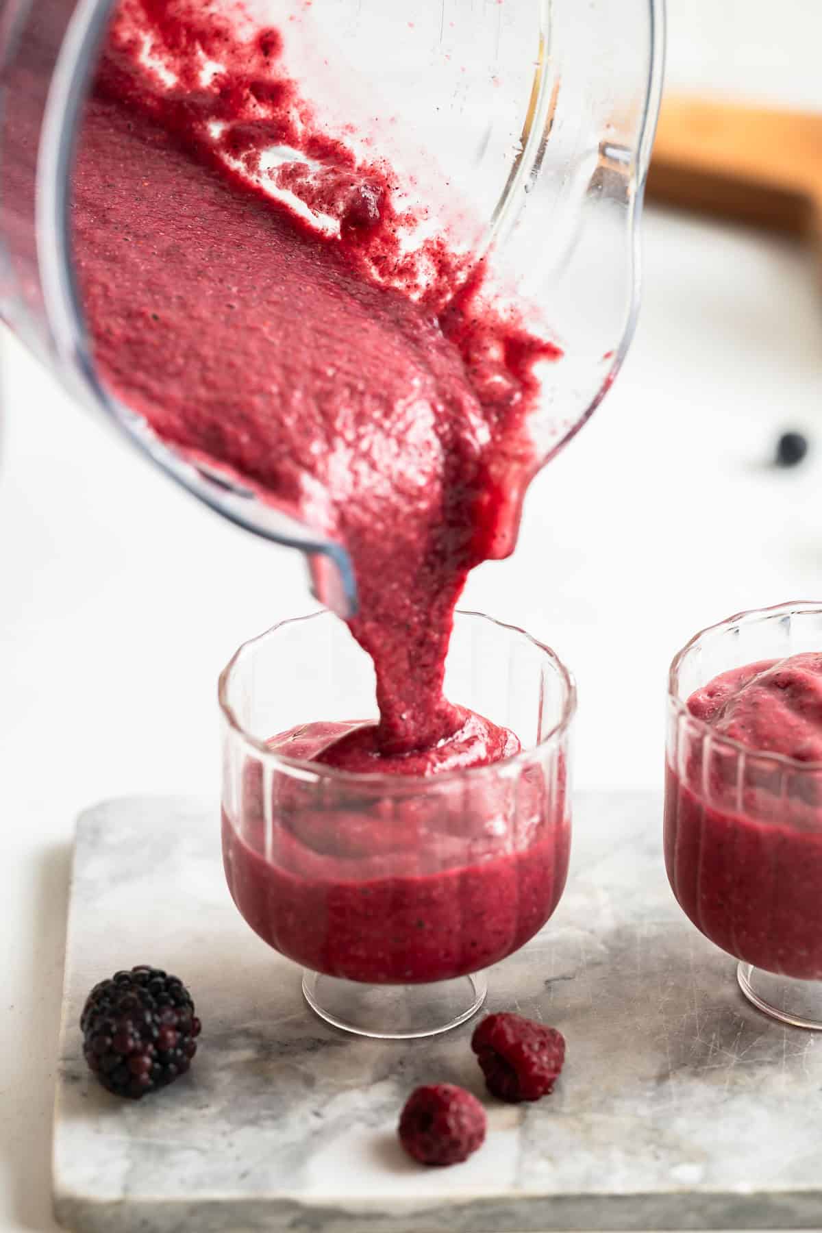 Pouring berry chia fruit smoothie into serving glasses