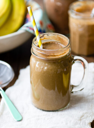 Delicious chocolate banana smoothie in a Mason jar with a yellow and white paper straw.