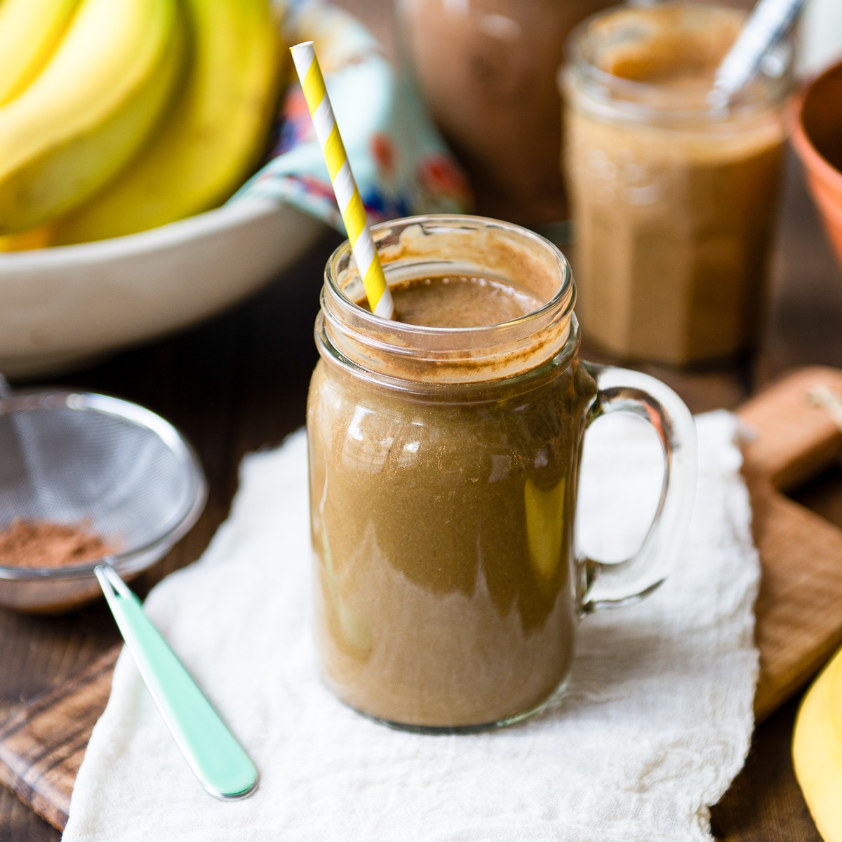 Delicious chocolate banana smoothie in a Mason jar with a yellow and white paper straw.